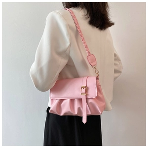 Detail of pink shoulder bag featuring pleated faux leather and woven strap design