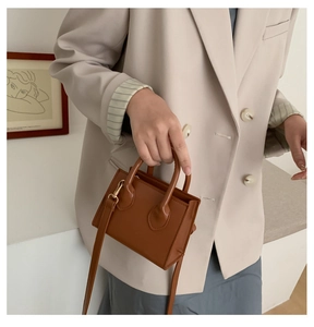 Detailed shot of brown leather mini crossbody bag with round handles and gold hardware