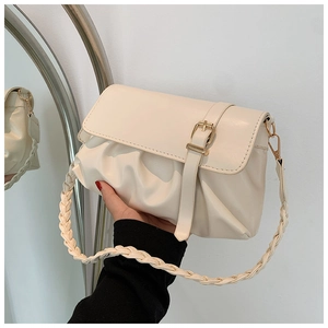 Detail of cream white pleated shoulder bag featuring metal buckle and woven strap design