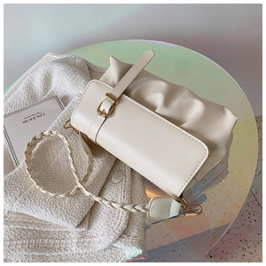 Detail of off-white pleated leather shoulder bag with woven strap and metal buckle