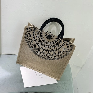 Detail of jute tote bag showing ethnic radial pattern and black woven handles