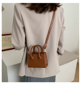 Brown leather mini crossbody bag styled on a beige blazer shown from a back view