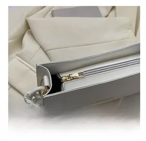 Detail view of smooth golden zipper closure on white leather underarm bag with fashion text