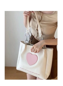 Detail of off-white tote bag featuring a pink heart graphic and metallic ring strap accents
