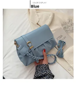 Detail of light blue shoulder bag with woven handle and metallic buckle on white linen
