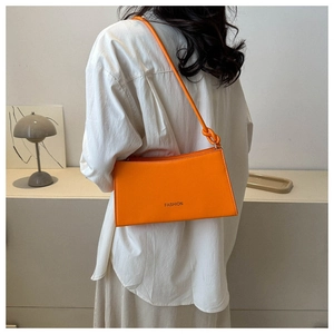 Detail of vibrant orange FASHION baguette bag worn as a stylish underarm shoulder bag