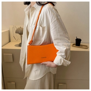 Detail of a bright orange shoulder bag featuring the word FASHION with a knotted strap