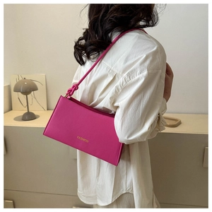 Close-up of hot pink leather baguette bag with fashion lettering and knotted strap detail
