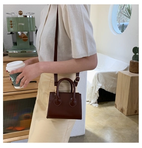 Detail of dark brown mini crossbody bag with gold hardware and smooth synthetic leather