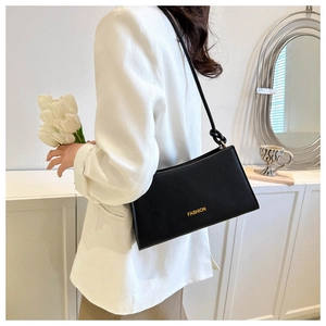 Side view of a black leather underarm bag with gold FASHION text on a white blazer
