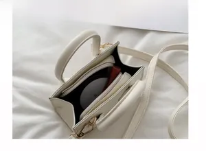 Interior view of cream crossbody bag featuring central zipper pocket and compartment