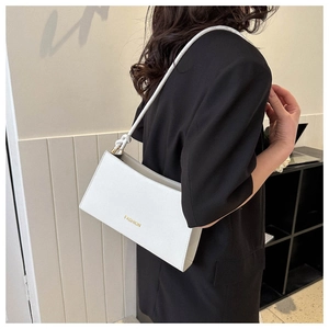 Side view of white leather underarm bag with gold FASHION lettering and knotted strap