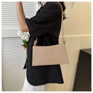 Close-up of beige shoulder bag with knot detail and gold FASHION lettering text