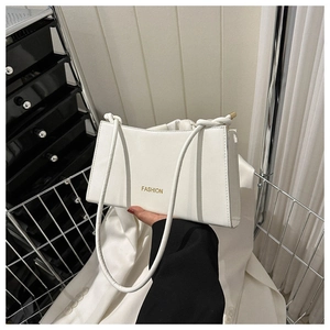 Detail of white leather baguette bag with gold FASHION lettering and slim strap