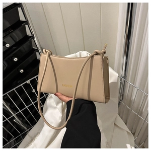 Detail of beige leather shoulder bag with gold Fashion text and knot strap design