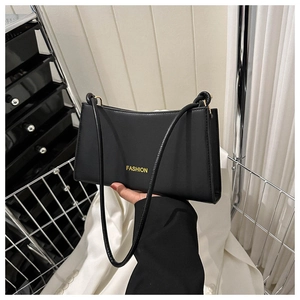 Detail of minimalist black leather baguette bag with yellow FASHION lettering