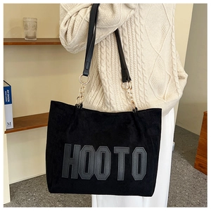 Detail of black tote bag with HOOTO letter patch and metal chain strap attachment