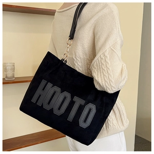 Black velvet tote bag detail showing luxury gold chain strap and stylish logo design