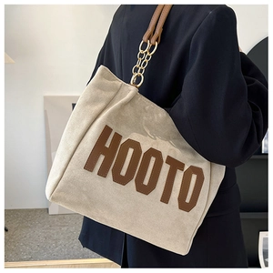 Detail of suede tote bag with HOOTO lettering and gold chain leather shoulder strap