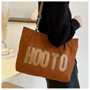 Detail of brown corduroy tote bag with large HOOTO letter patch and chain strap