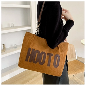 Detail of a large brown suede tote bag with HOOTO letter patches and metal chain straps