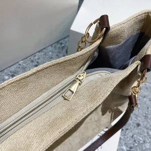 Detail of light gold zipper closure and chain strap on beige suede tote bag