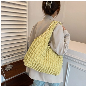 Close-up of bright yellow popcorn texture tote bag worn over shoulder on stylish outfit
