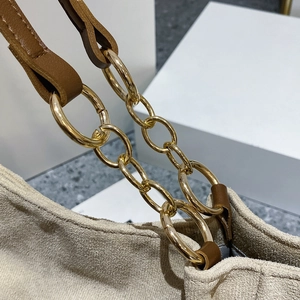 Detail of khaki suede tote bag showing premium gold metal rings and brown leather strap