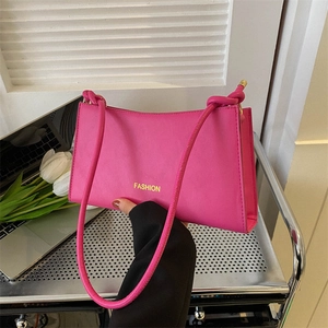 Rose pink baguette shoulder bag with knot strap and yellow Fashion text in a lifestyle setting
