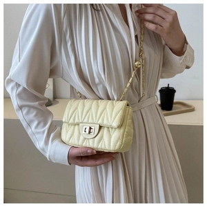 Détail du sac bandoulière beige matelassé avec chaîne dorée et fermoir tournant en métal