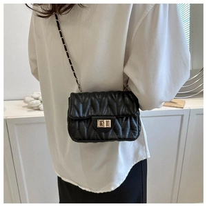 Détail d'un sac bandoulière noir matelassé avec chaîne dorée et fermoir pivotant