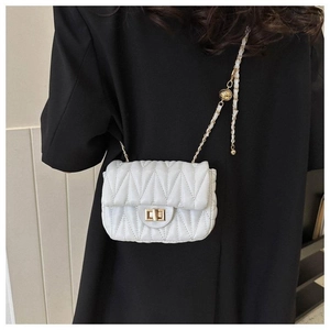 Détail du sac matelassé blanc avec fermoir tournant doré et chaîne à boule ajustable