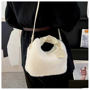 Détail du sac à main en peluche blanche avec poignée en similicuir et breloque dorée