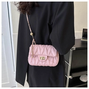 Détail du sac à bandoulière rose clair matelassé avec chaîne dorée et breloque