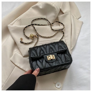 Détail de la texture en cuir noir matelassé et de la bandoulière chaîne dorée du sac