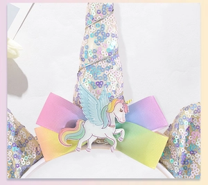 Macro view of unicorn headband with sequins, rainbow bow and Pegasus figurine