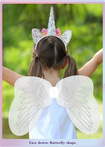 Detail of glitter unicorn headband and white butterfly wings costume for girls