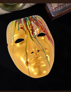 Artistic gold masquerade mask with colorful paint drip details and black elastic strap
