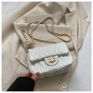 Détail du sac matelassé blanc avec fermoir rotatif doré et bandoulière en chaîne chic