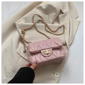 Détail d'un sac à main rose matelassé avec fermoir doré rotatif et bandoulière chaîne