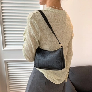 Détail de la texture crocodile noire et de la fermeture éclair du sac à bandoulière
