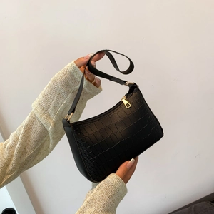 Détail d'un sac à bandoulière noir à motif crocodile avec fermeture éclair dorée
