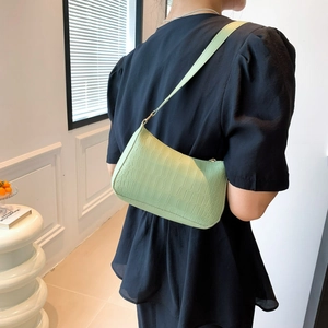 Détail du sac baguette vert menthe avec texture crocodile porté par un mannequin