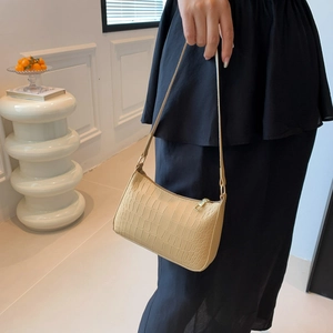 Gros plan sur la texture crocodile beige et la fermeture éclair du petit sac à bandoulière