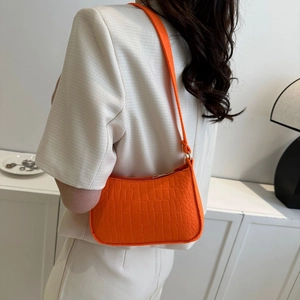 Détail de la texture cuir de crocodile orange vif sur un sac baguette de style vintage