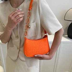 Détail d'un sac orange vif en similicuir à texture crocodile et bandoulière en acrylique