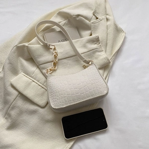 Gros plan du sac baguette blanc cassé avec motif crocodile et chaîne dorée chic