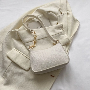 Détail d'un sac sous les aisselles blanc en similicuir crocodile avec chaîne dorée