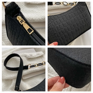 Détail de la texture cuir crocodile noir et des fermetures éclair dorées du sac
