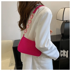 Gros plan sur le sac fuchsia à motif crocodile avec une chaîne rose assortie sur modèle